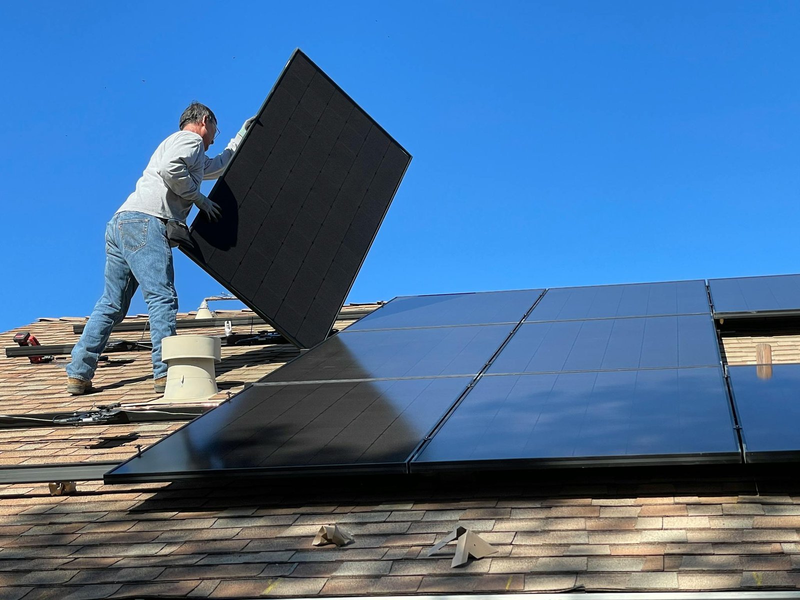 A worker installs solar panels on a sunny day, highlighting renewable energy solutions.